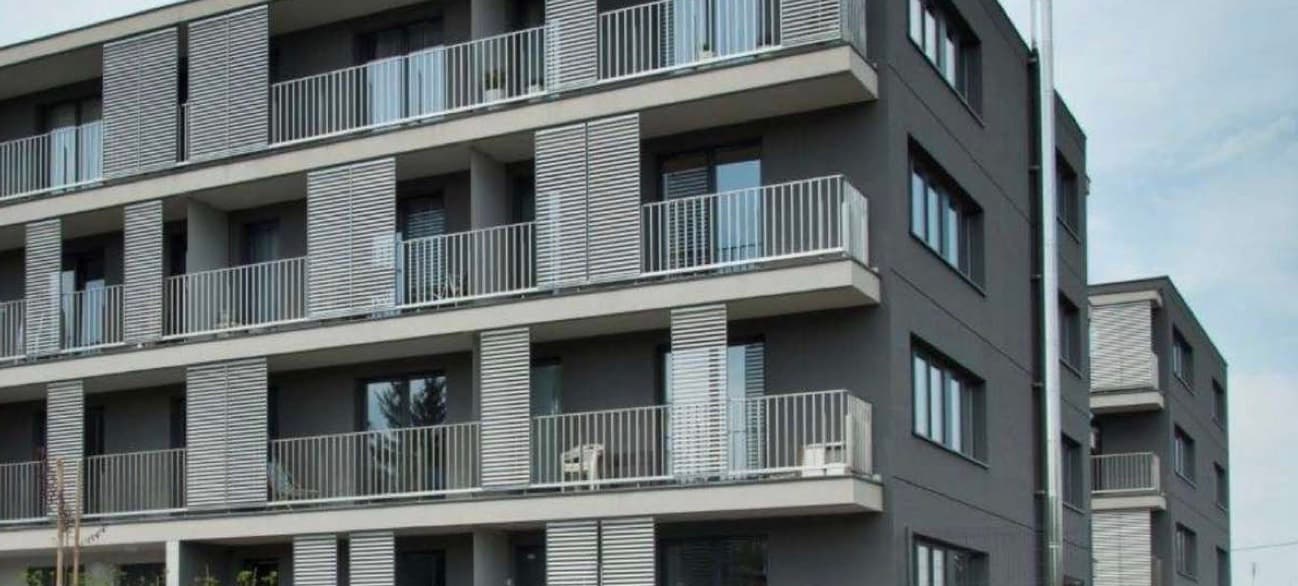 Skowronia II — Gebäudeecke mit auskragenden Balkonen und Metall-Läden